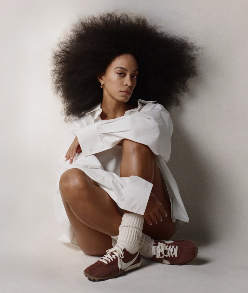 Mannequin portant des sneakers Jacquemus x Nike avec une chemise blanche oversize, photographié dans un studio minimaliste pour la campagne de la collaboration