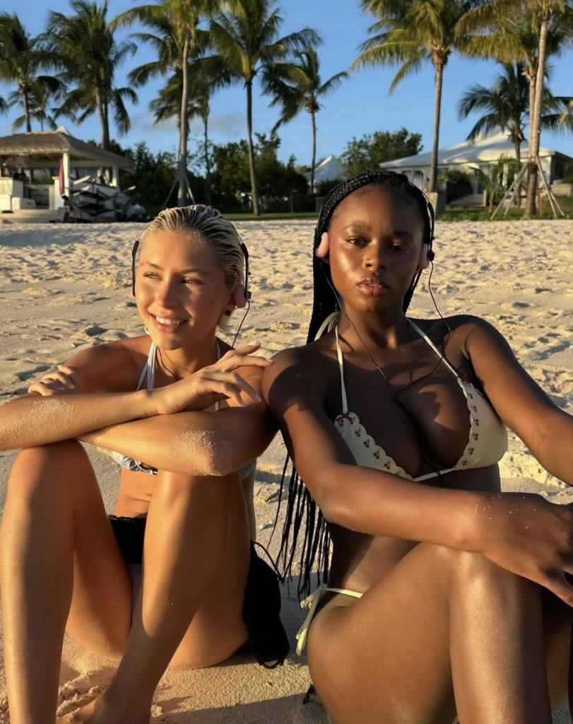 Deux mannequins assises sur une plage de sable à l'heure dorée, portant des bikinis de la collaboration Victoria's Secret PINK x Frankies Bikinis Surf House