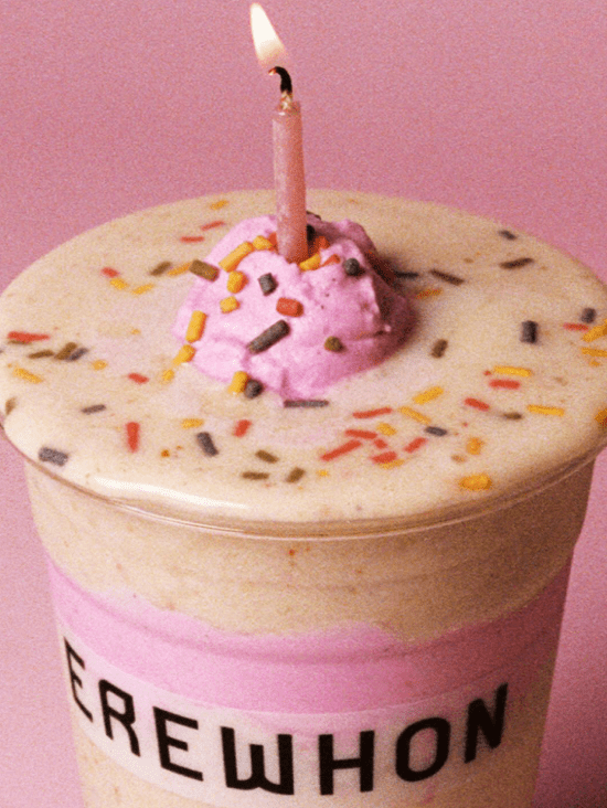 Smoothie anniversaire Erewhon surmonté d'une bougie rose, de sprinkles et d'une rosette de crème, issu de la collaboration édition limitée Erewhon x Barbie