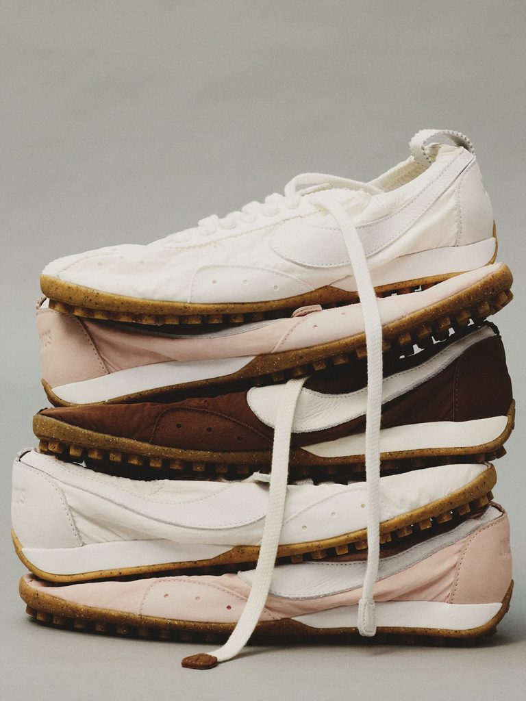 Pile de sneakers Jacquemus x Nike dans des tons neutres — blanc, blush et marron — avec une semelle gomme et un lacet blanc passé à travers
