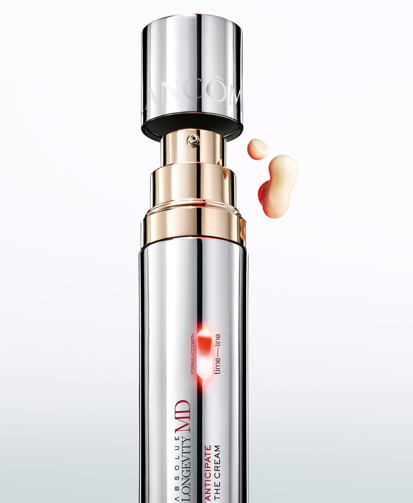 Gros plan du flacon-pompe du sérum Lancôme Absolue Longevity MD avec des gouttes de produit, issu de la collaboration Lancôme x The Devil Wears Prada 2