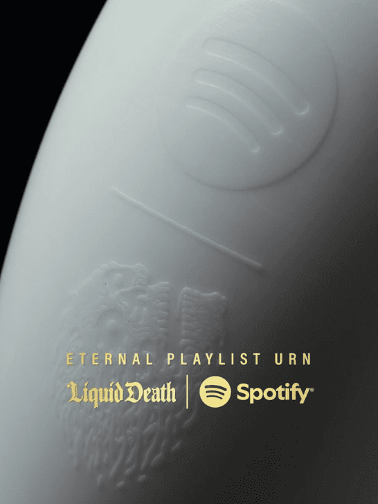 Gros plan de l'Eternal Playlist Urn de Liquid Death x Spotify en blanc mat, gravé des logos des deux marques et du nom du produit en lettres dorées